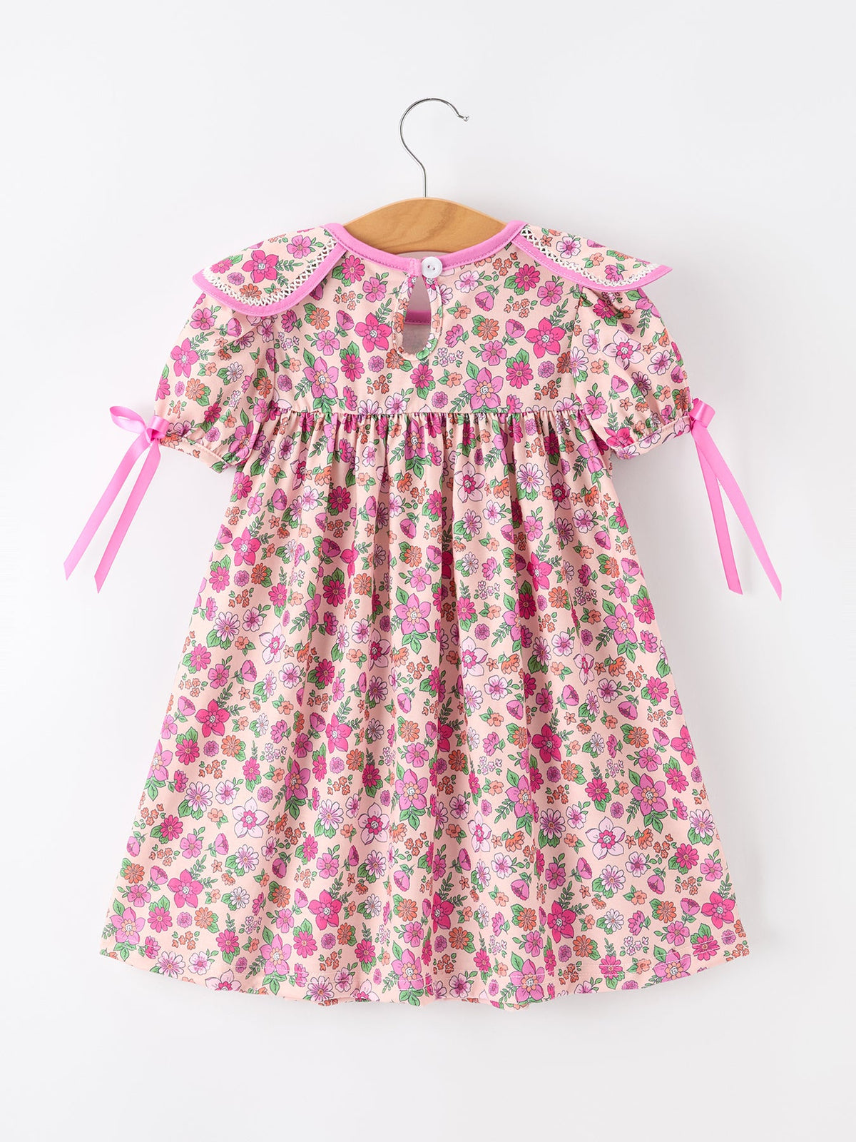 a pink and white dress with pink bows on a swinger
