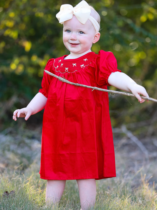 a child in a red dress holding a stick