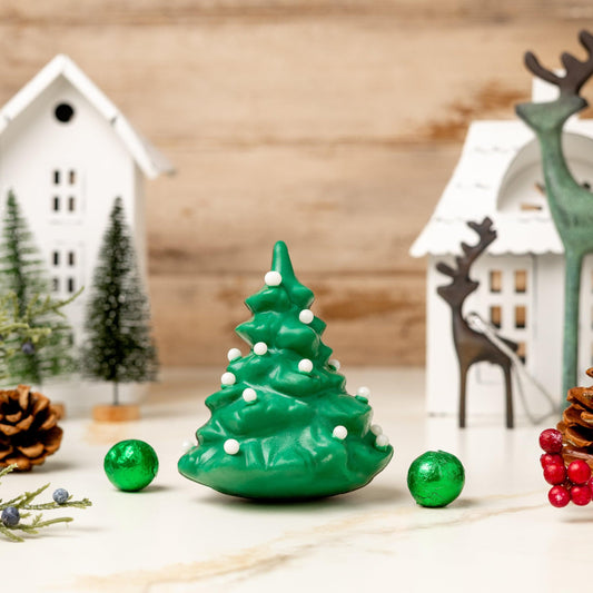 a green christmas tree and pine cones and a white house