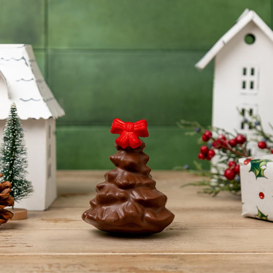 a chocolate tree with a red bow on top of a small white house