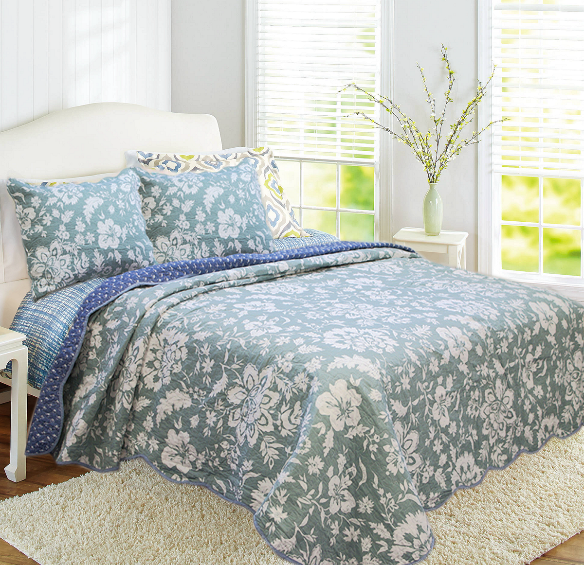 a bed with a floral blanket and pillows