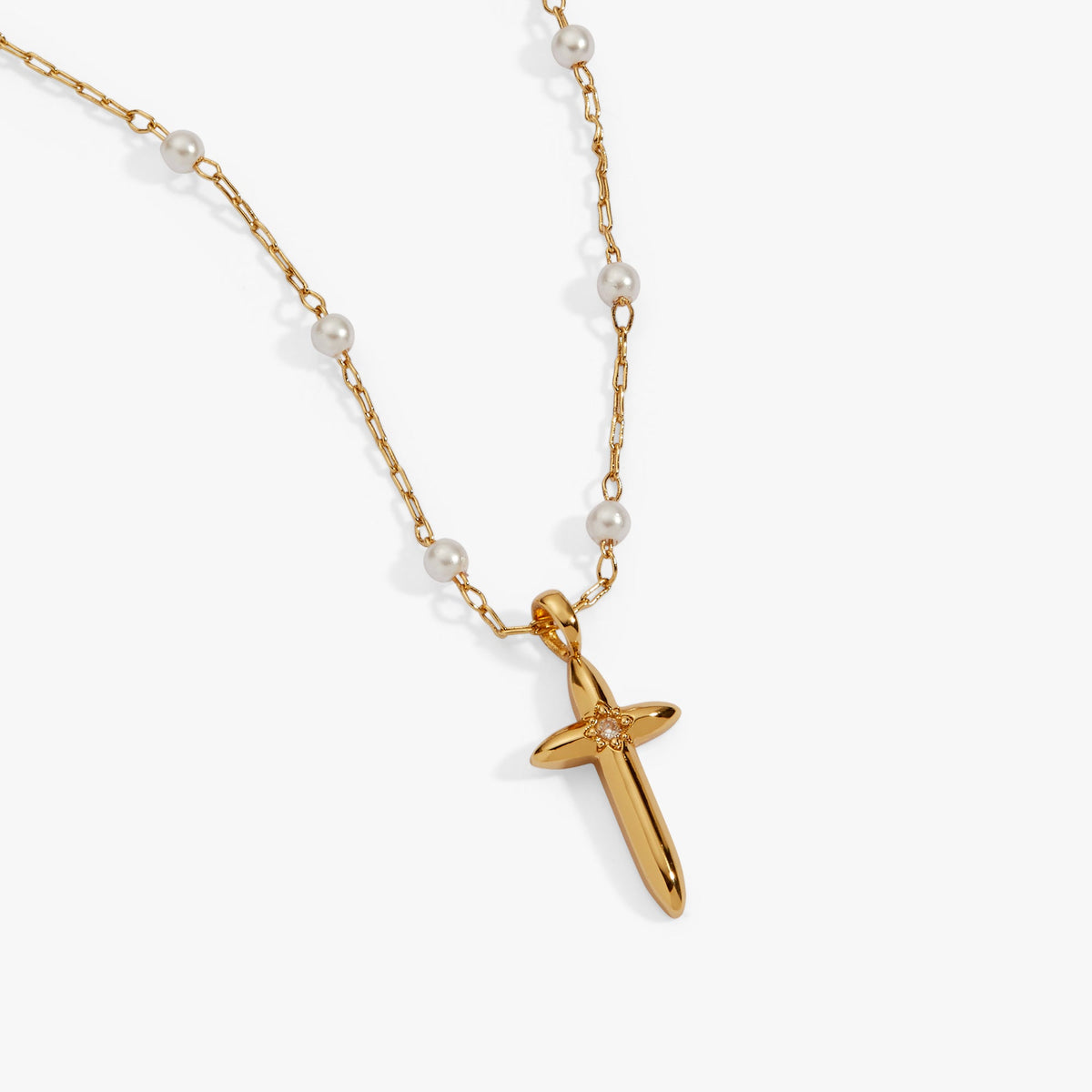 a gold cross necklace with pearls
