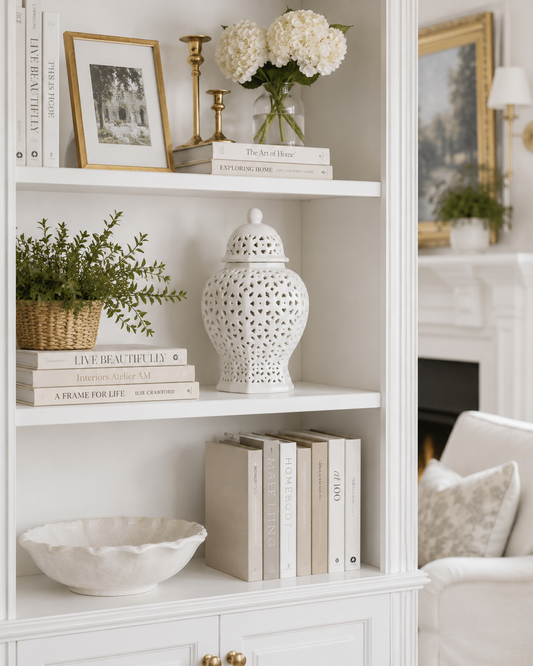 a white shelf with books and vases and flowers