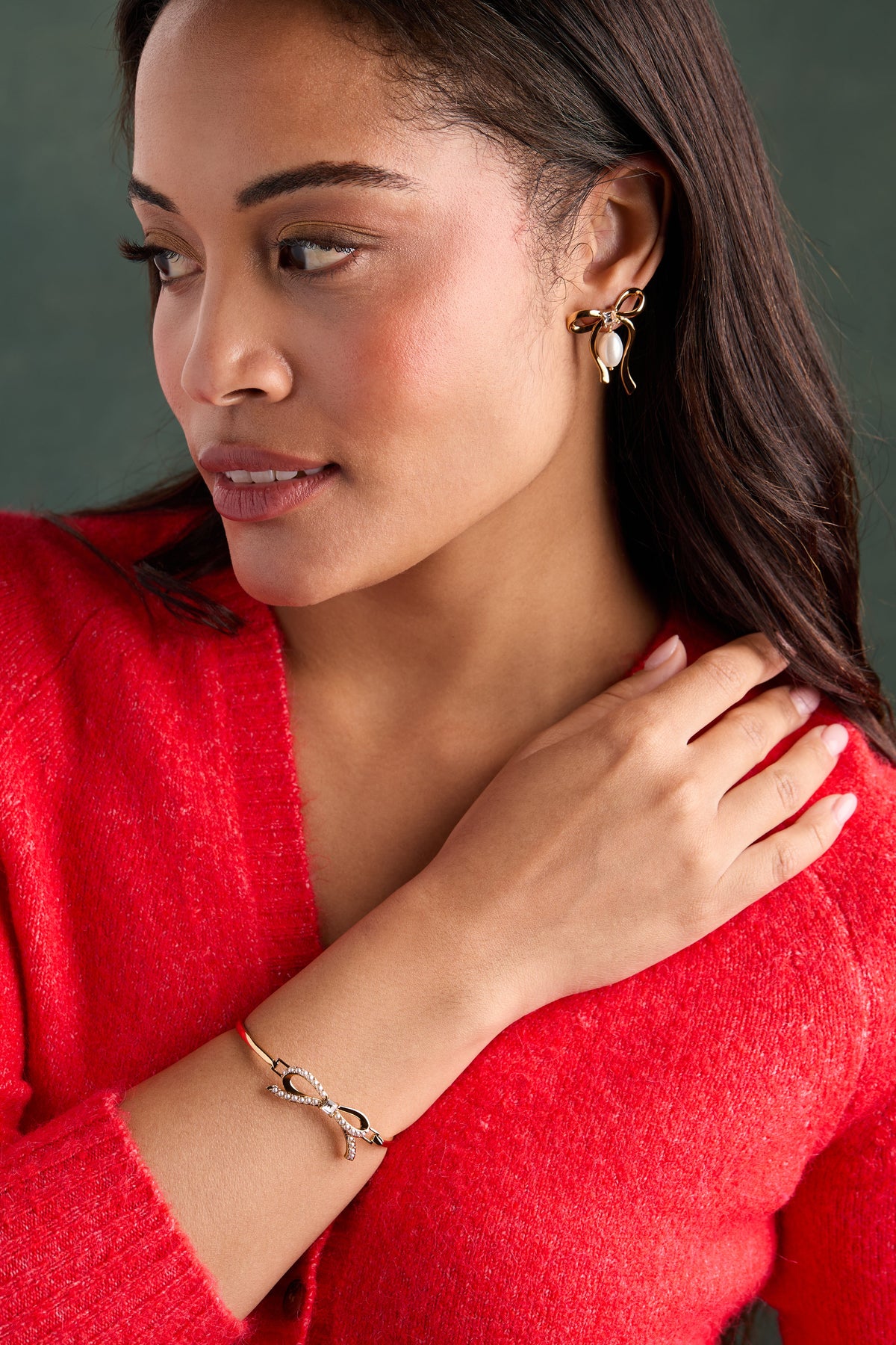 a woman wearing a red sweater and gold jewelry