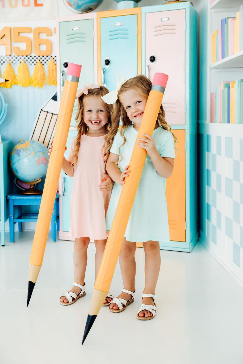 two girls holding large pencils