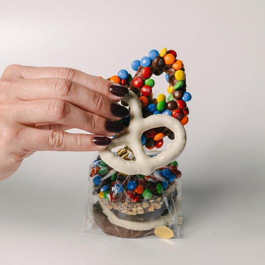 a hand holding a pretzel and candy
