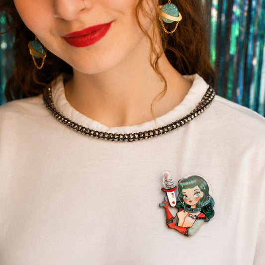 a woman wearing a white shirt with a cartoon pin on her chest