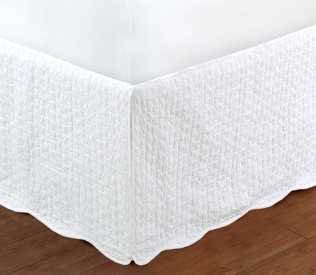 a white bed skirt on a wood floor