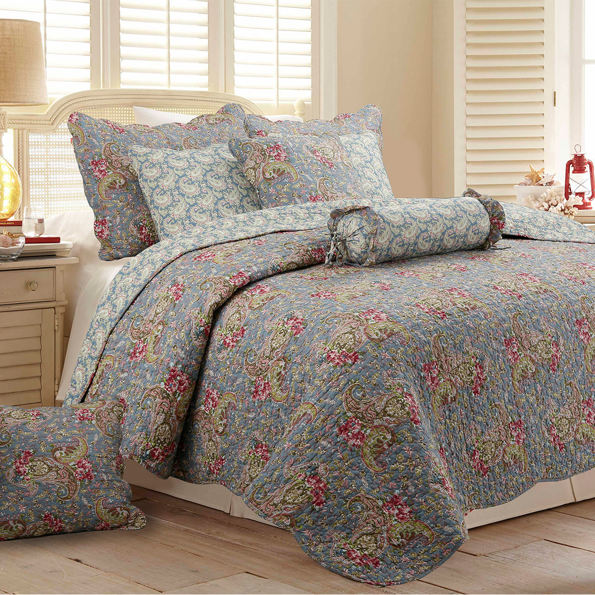 a bed with a floral comforter and pillows