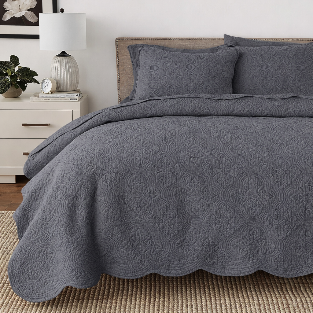 a bed with a grey comforter and pillows