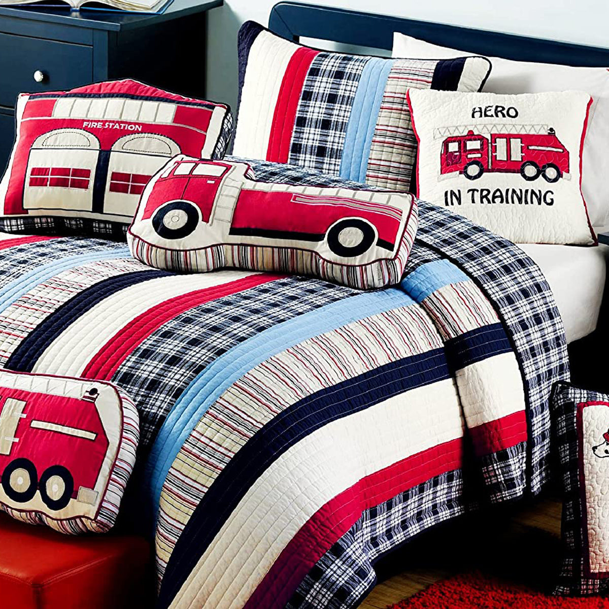 a bed with a firetruck pillow and pillows
