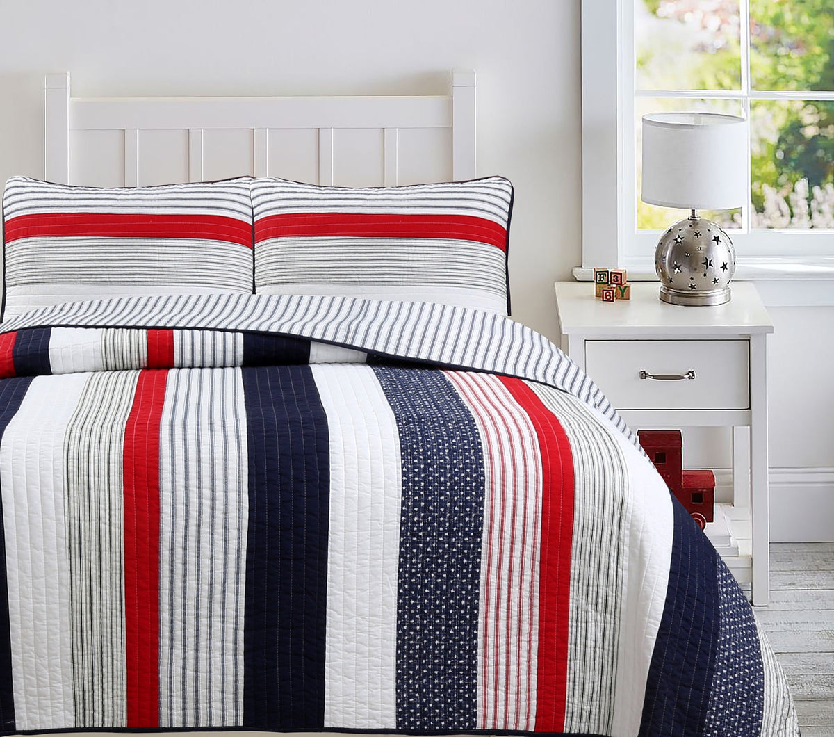 a bed with a striped bedding and a lamp
