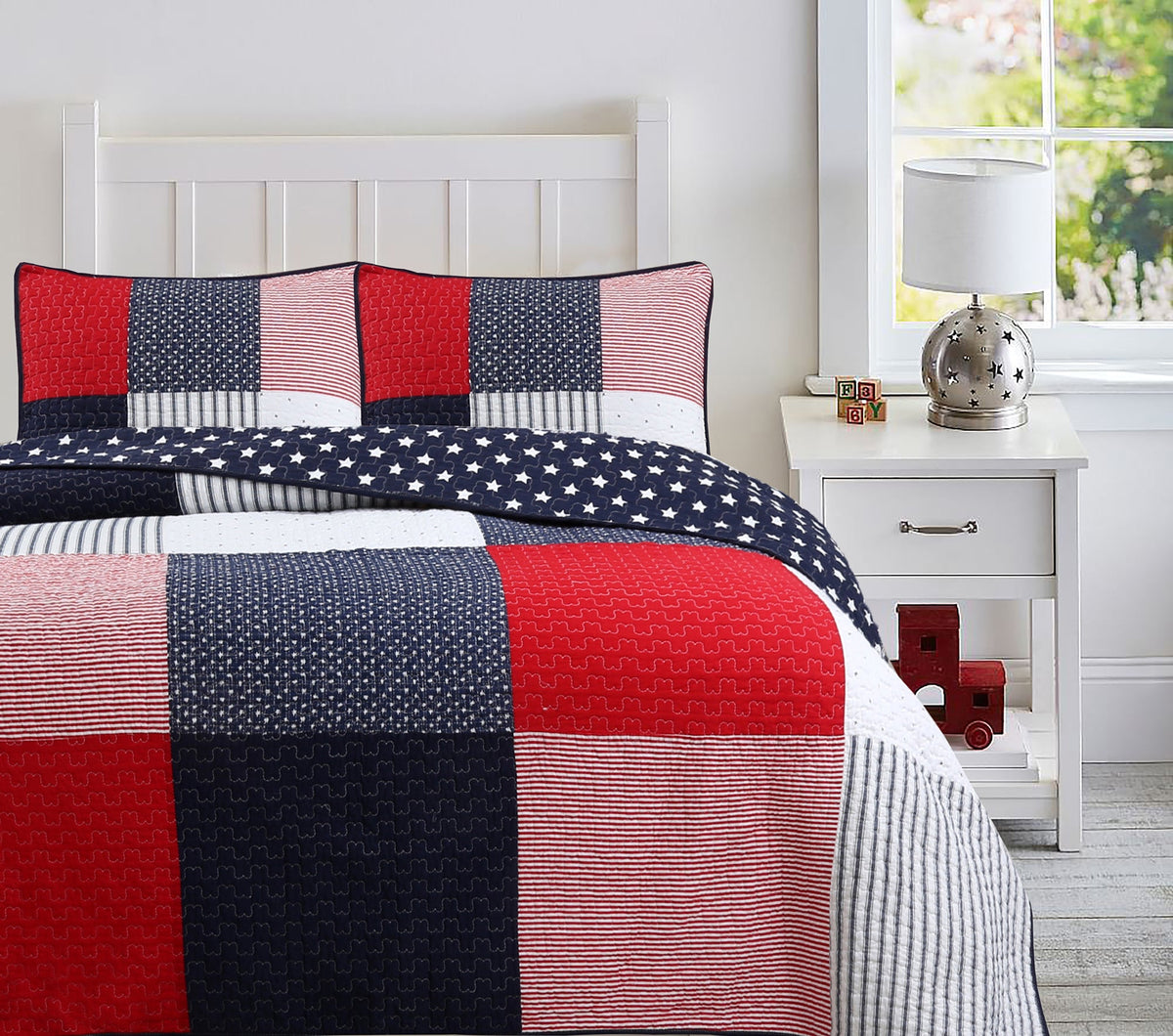 a bed with a quilt and a lamp