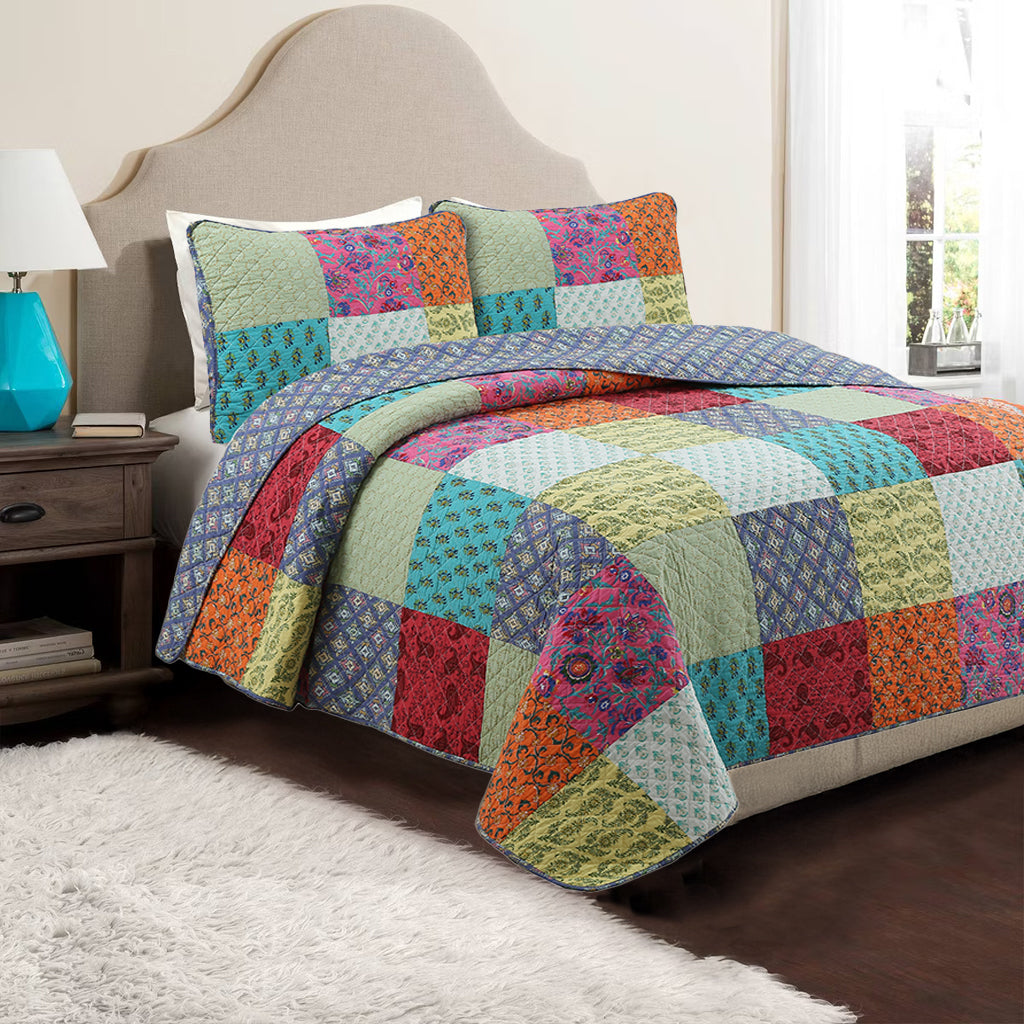 a bed with colorful quilt and a lamp on the side of the bed