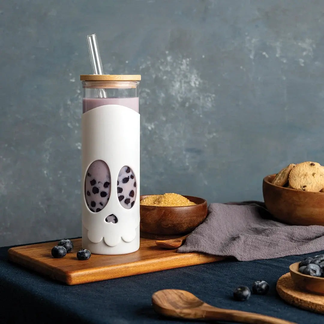 a glass bottle with a straw and a straw in it with a skull design on it