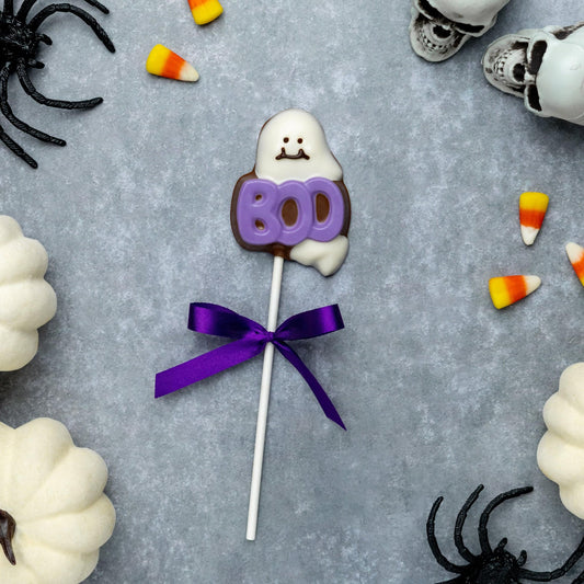 a candy on a stick next to a group of white pumpkins