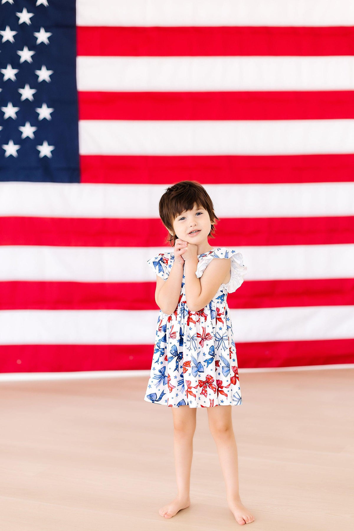 a girl in a dress with her hands together in front of a flag