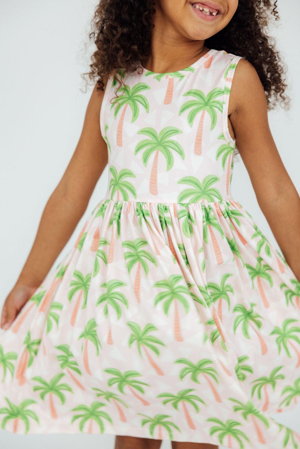 a girl wearing a dress with palm trees on it