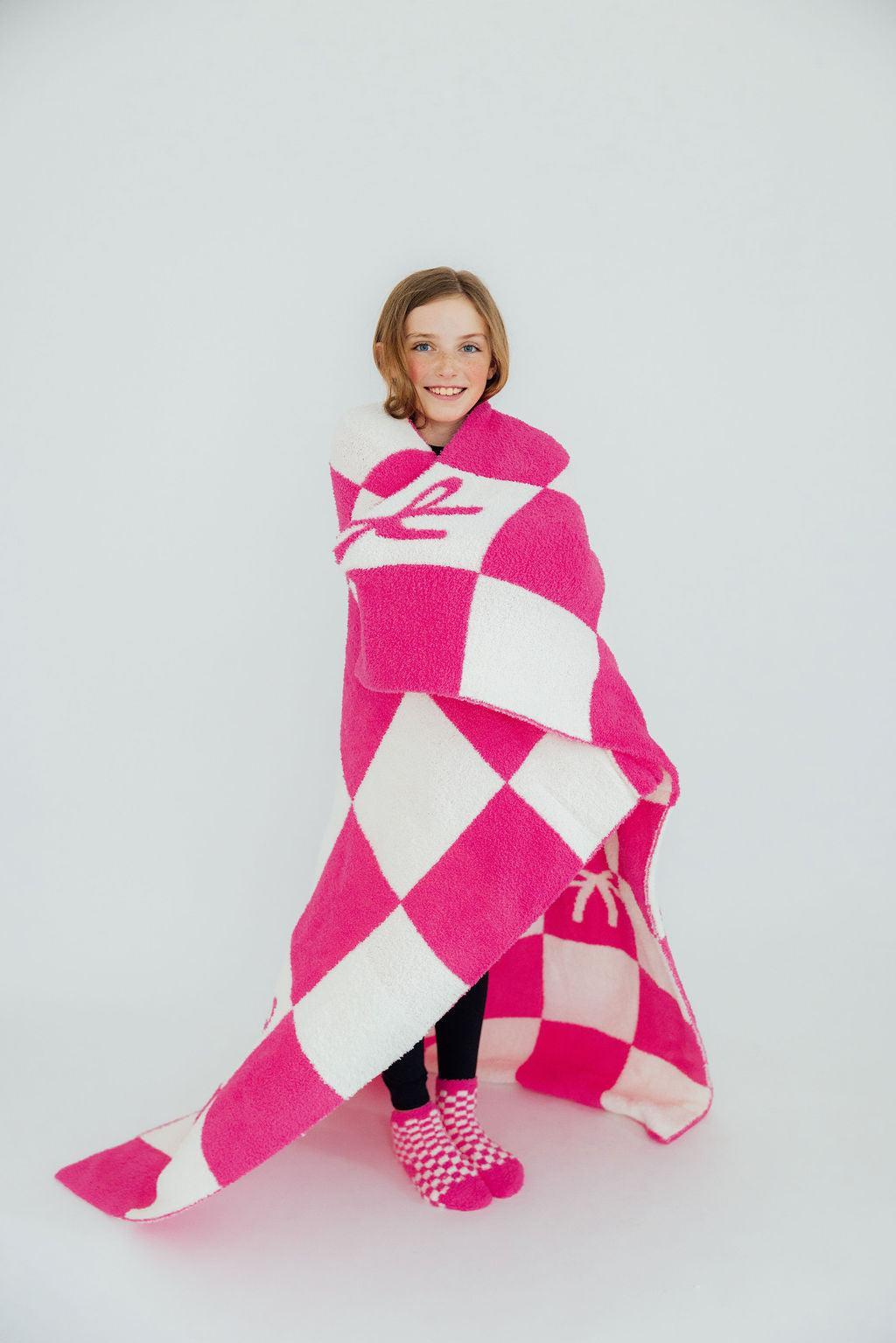 a girl wrapped in a pink and white checkered blanket