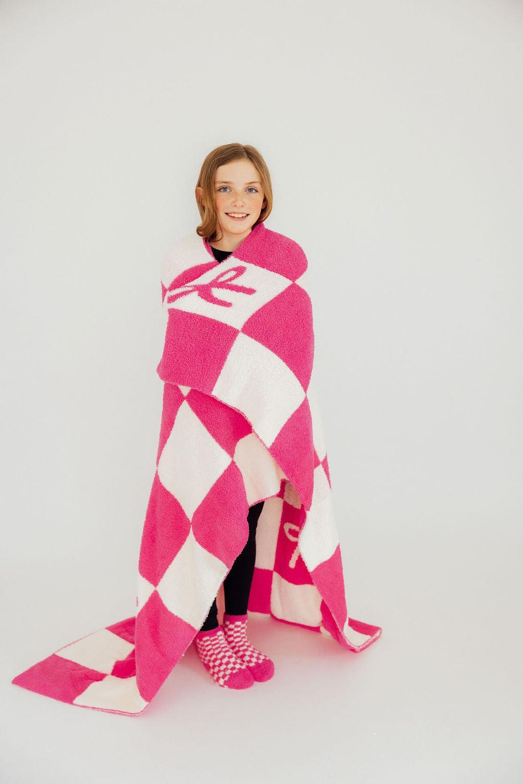 a girl wrapped in a pink and white checkered blanket