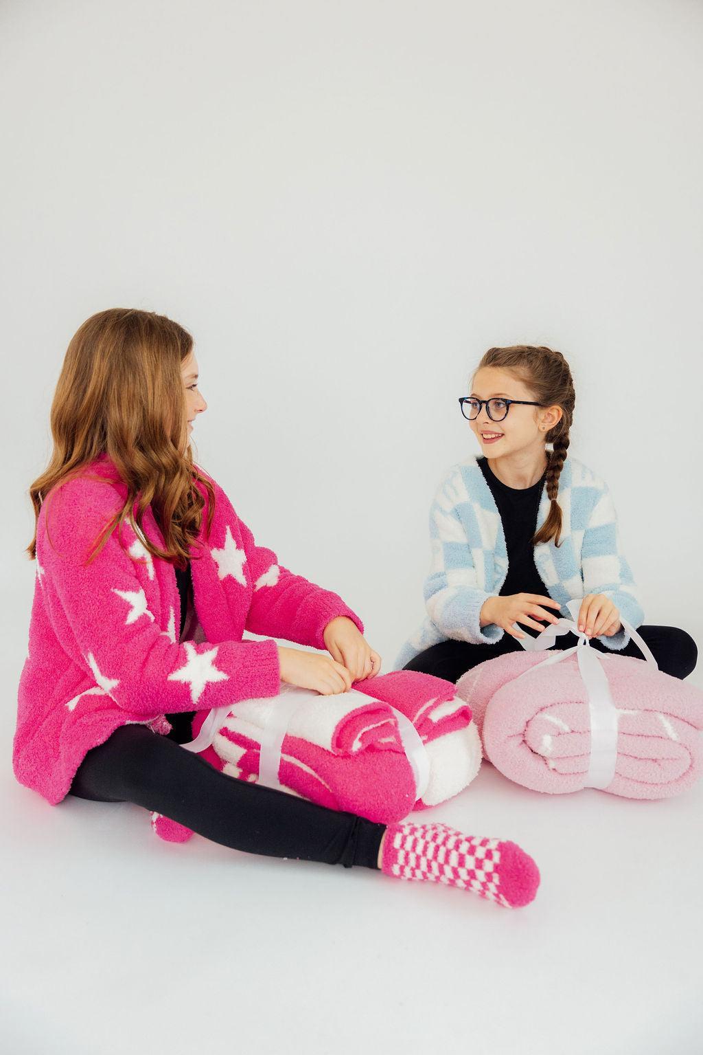 two girls sitting on the floor with blankets