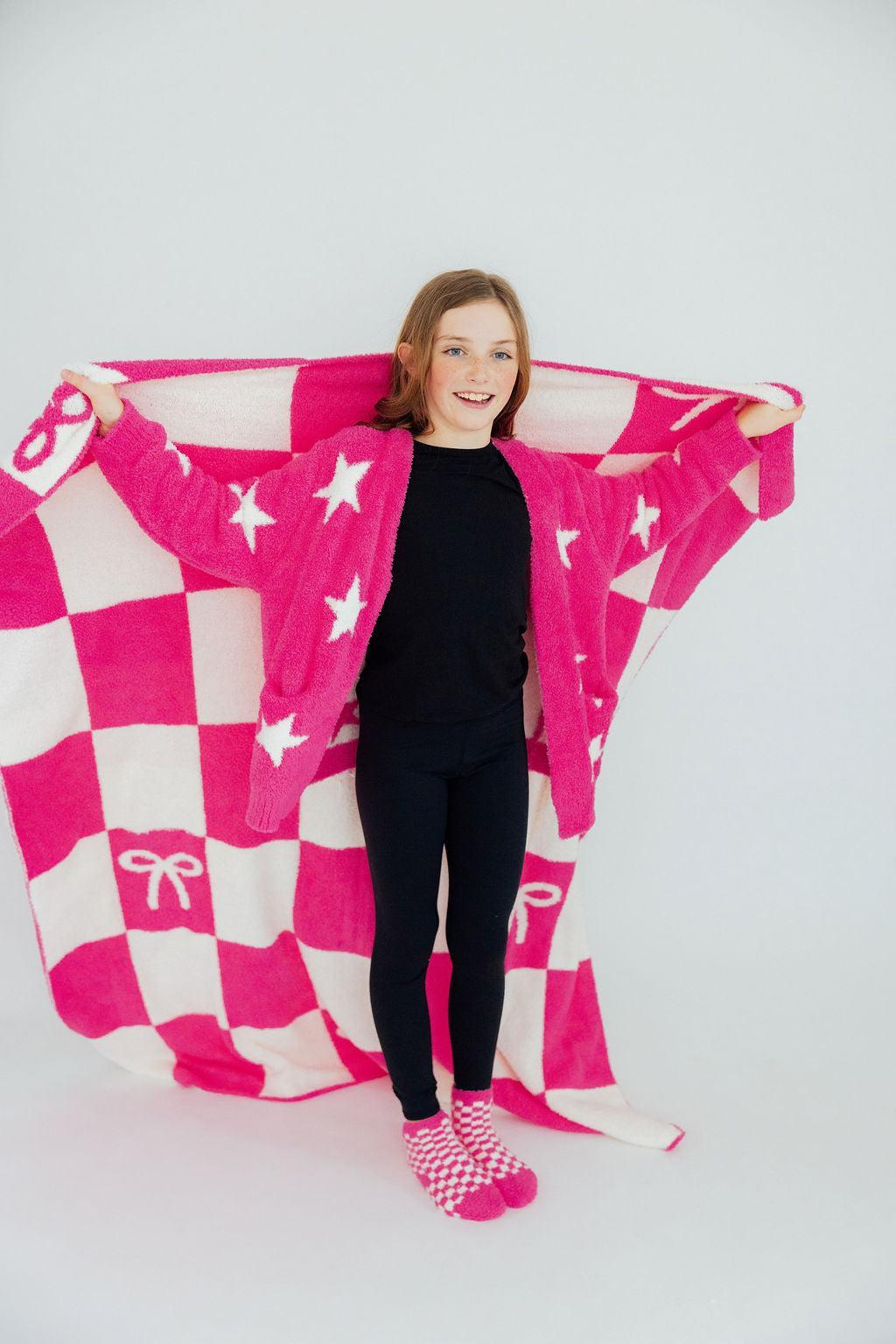 a girl holding a pink and white blanket