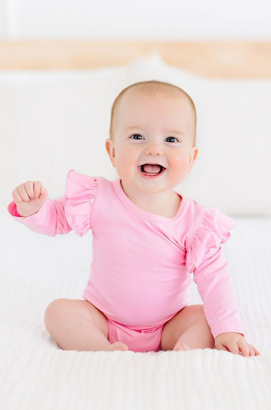 a baby sitting on a white blanket