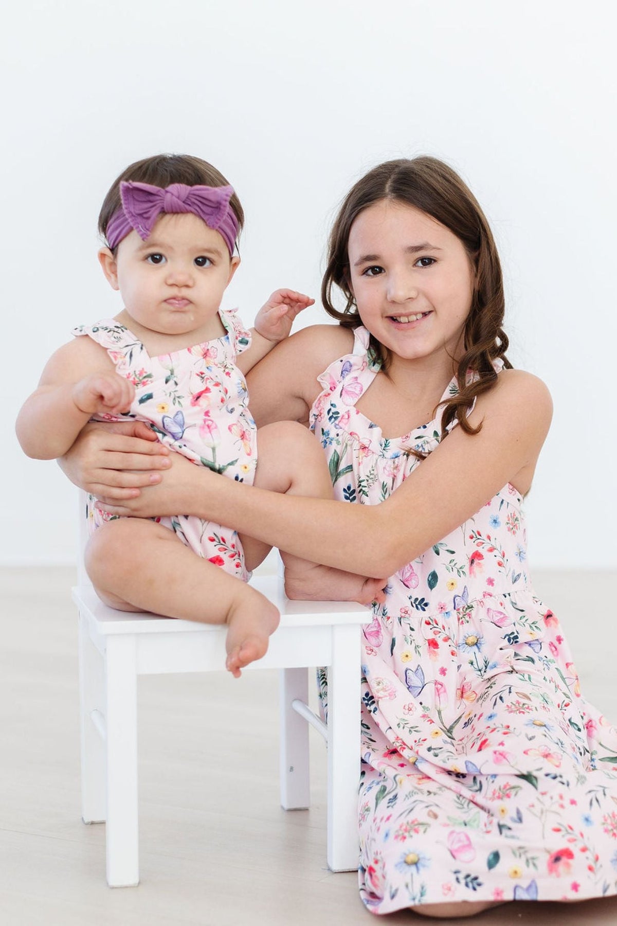 two girls sitting on a small stool
