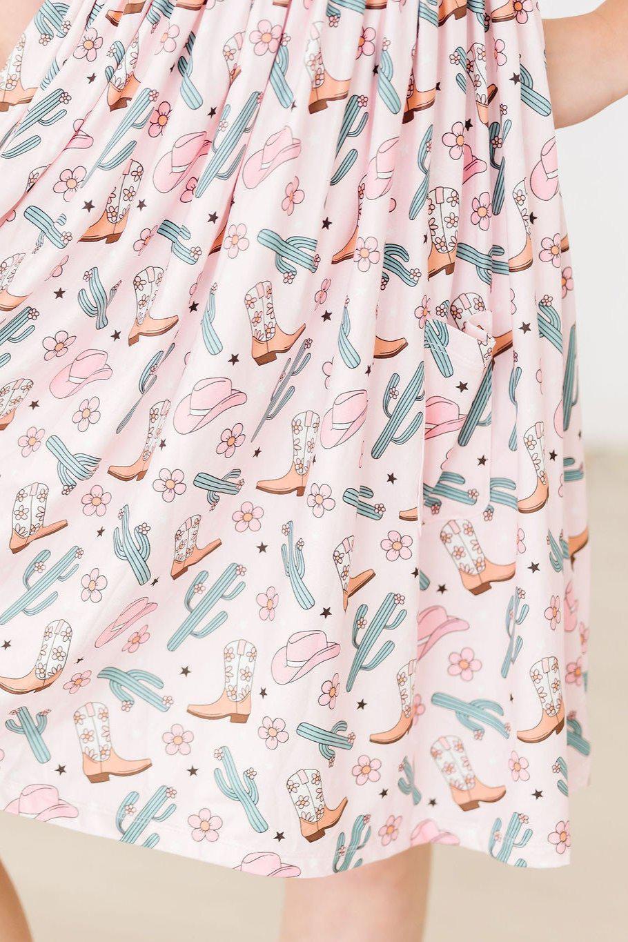 a pink skirt with cowboy boots and cactuses