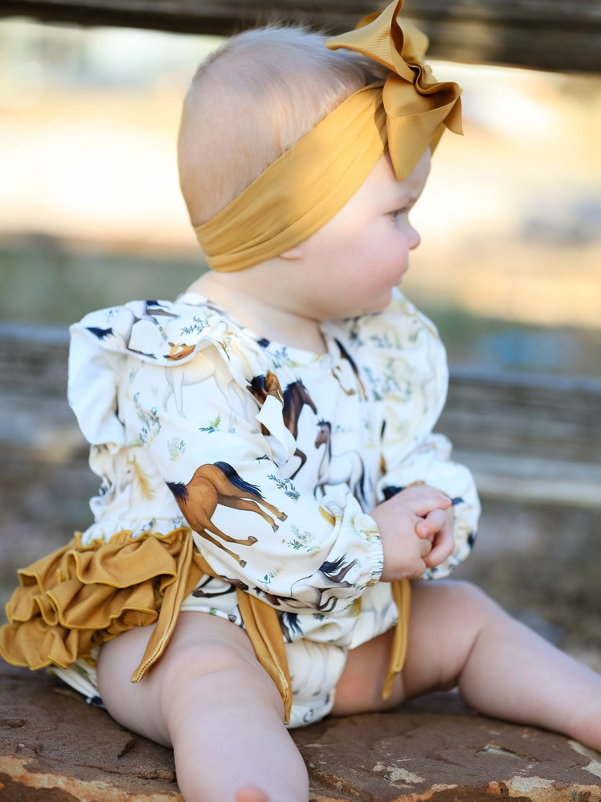 a baby girl sitting on a log