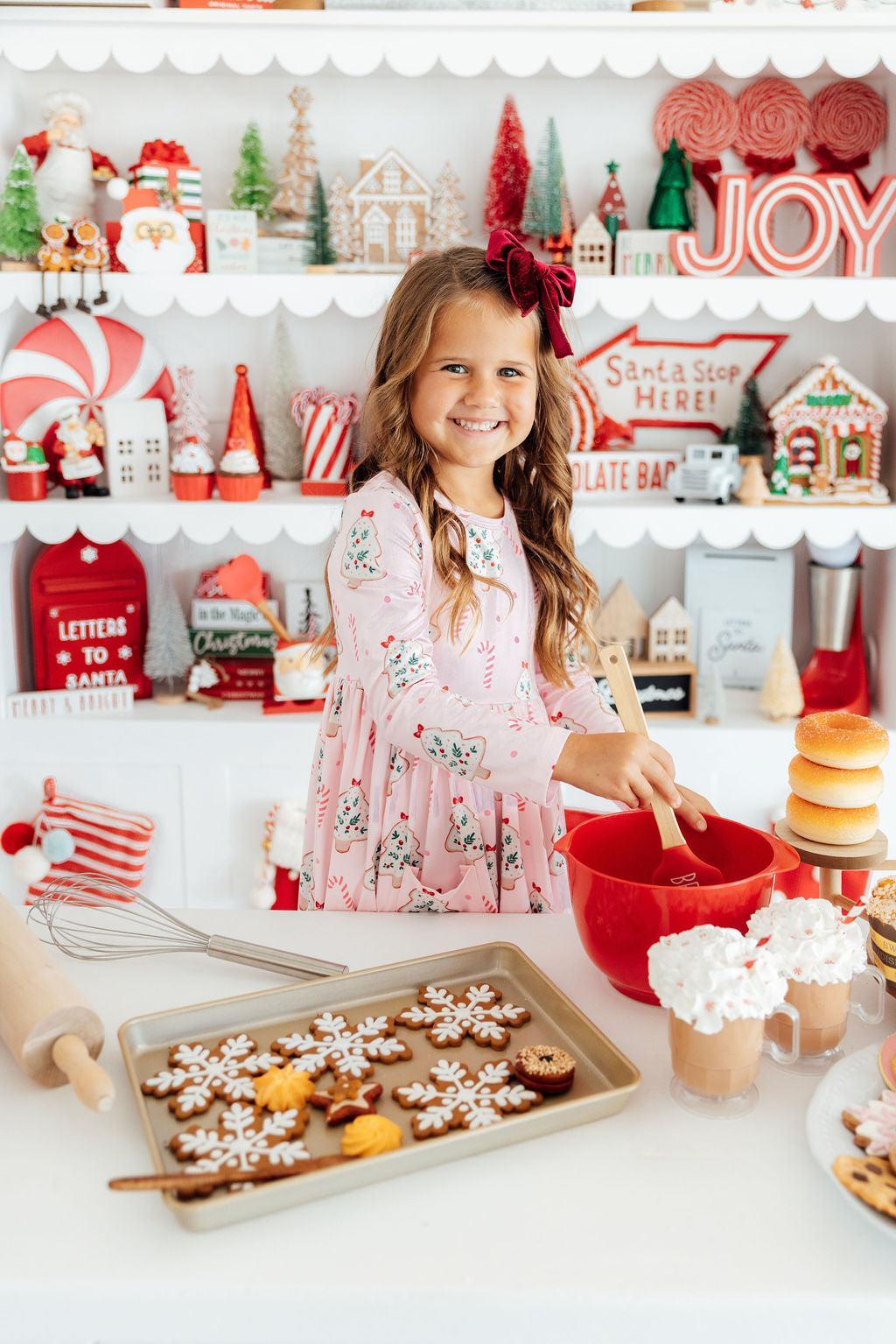 a girl in a pink dress making cookies