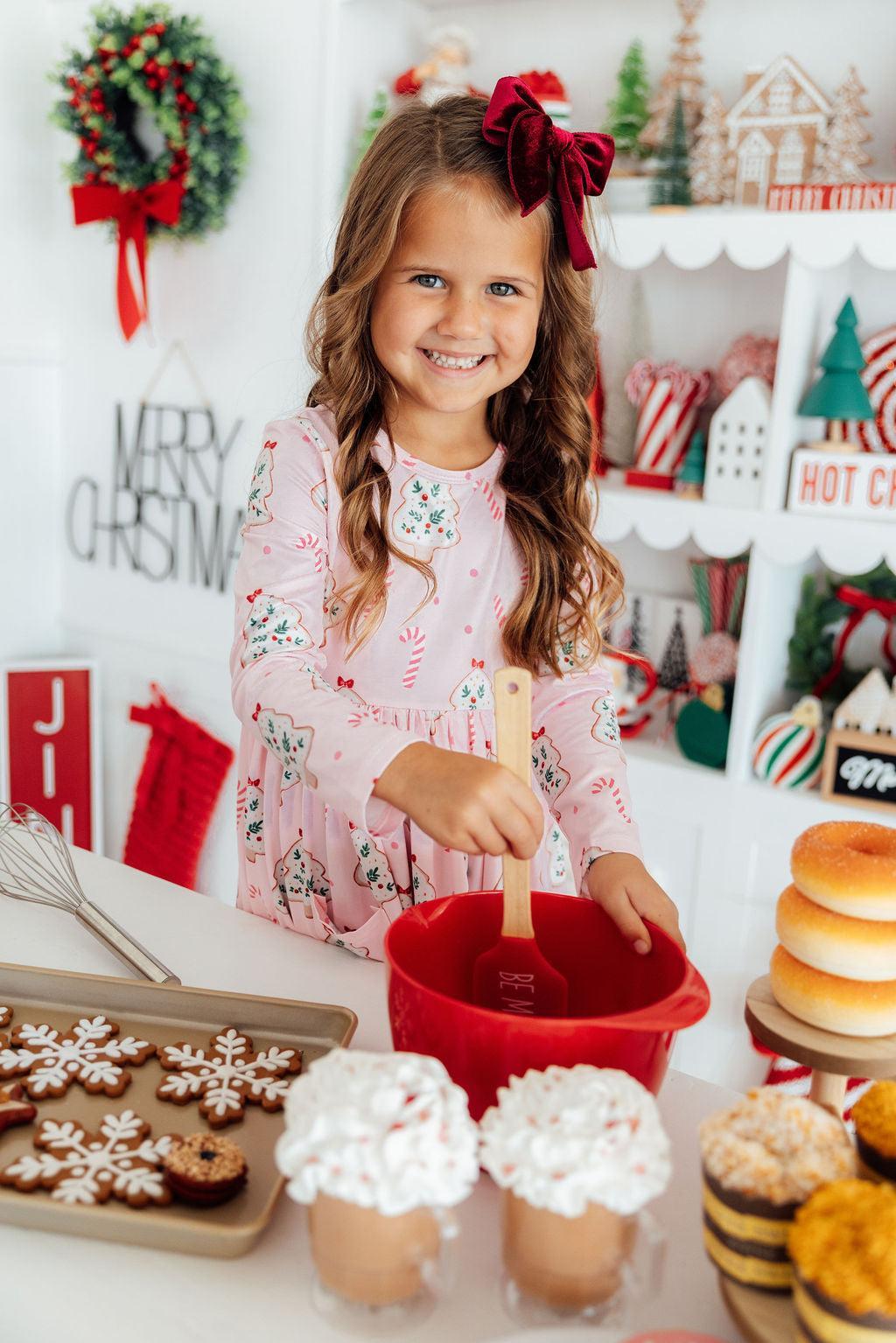 a girl in a pink dress mixing cookies