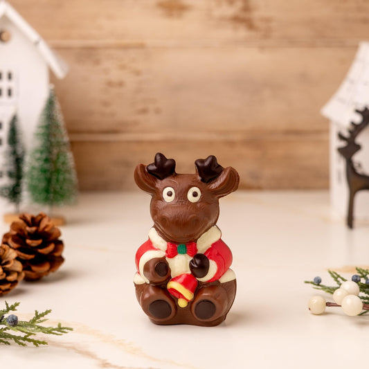 a chocolate moose with a red and white suit and a white house and pine cones