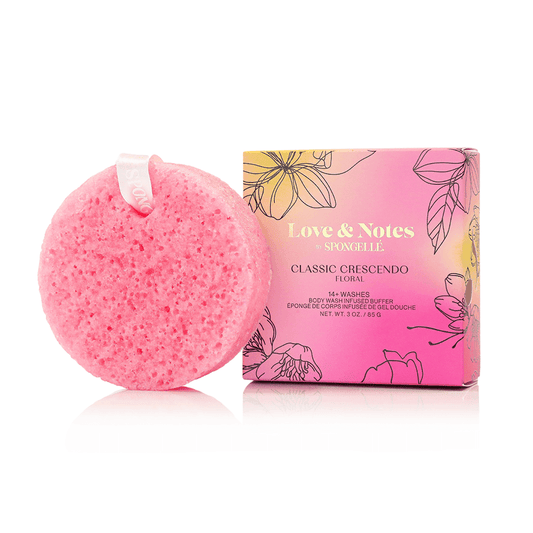 a pink sponge with a white ribbon next to a box