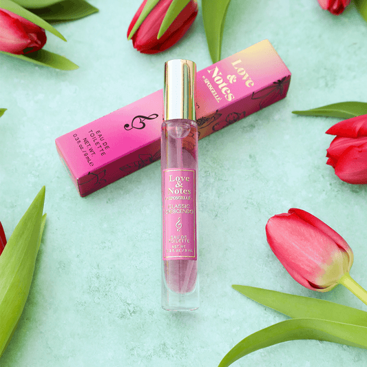 a pink perfume bottle next to pink box and red tulips