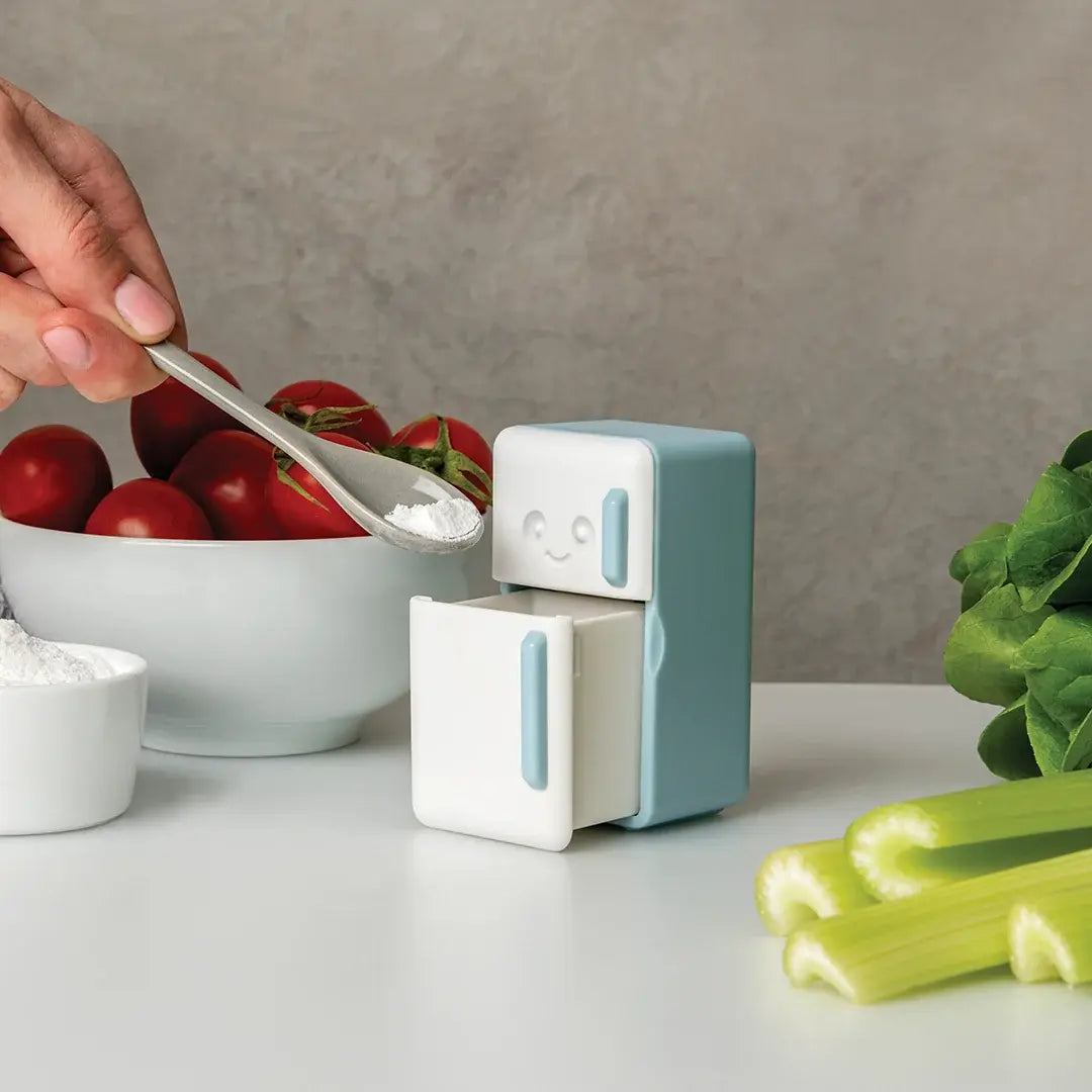 a person pouring powder into a small refrigerator