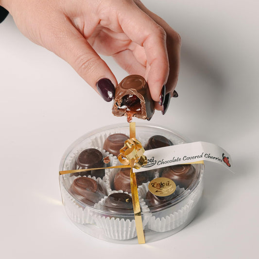 a hand holding a chocolate candy in a plastic container
