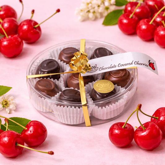 a round container with chocolates in it next to cherries