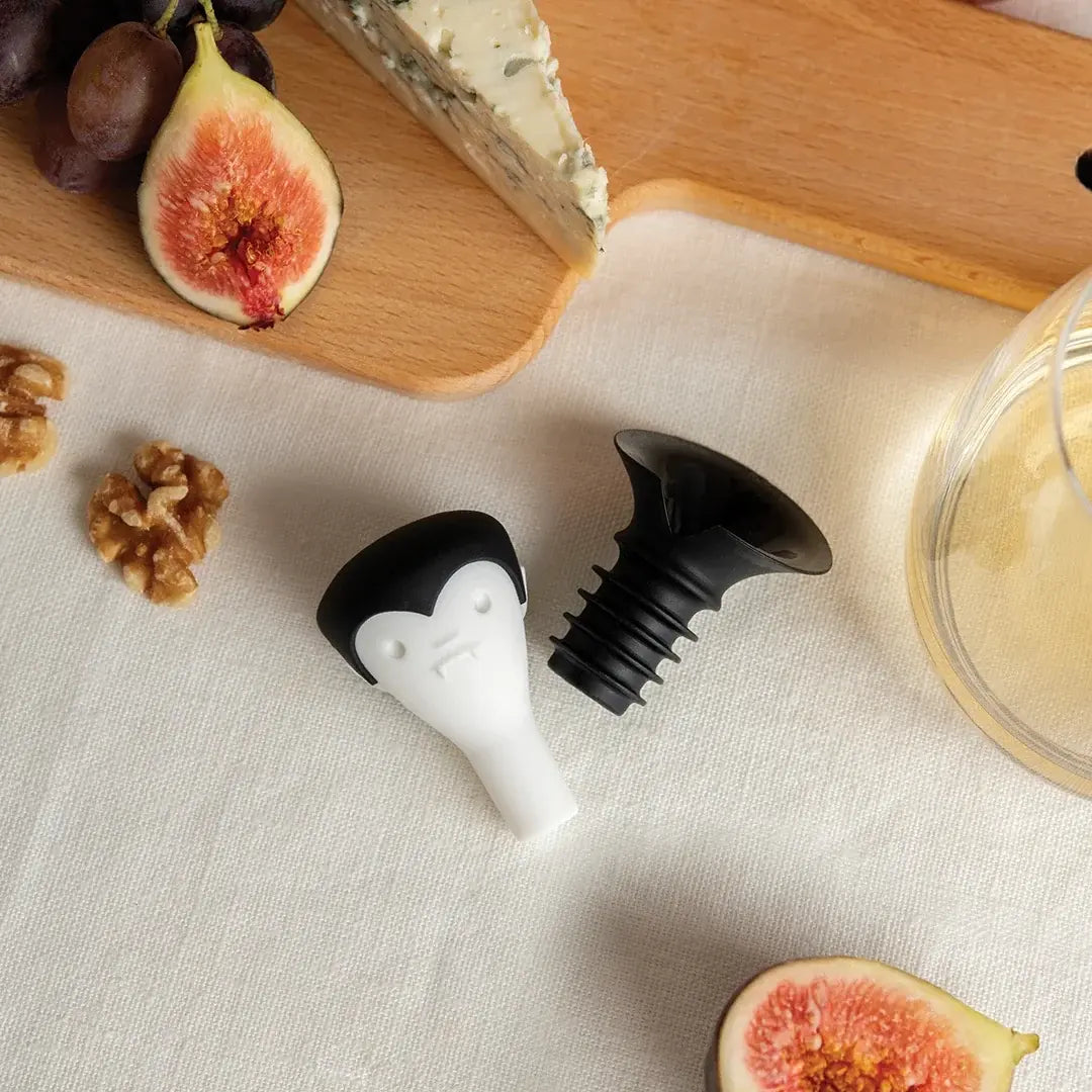 a cheese board with a couple of figs and a glass of wine