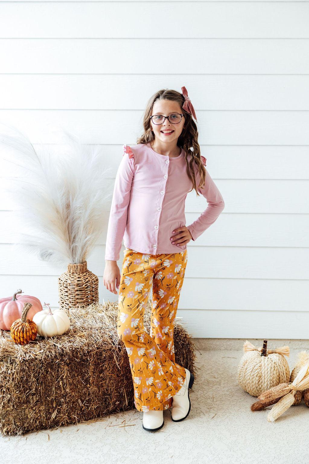 a girl standing in front of a hay bale