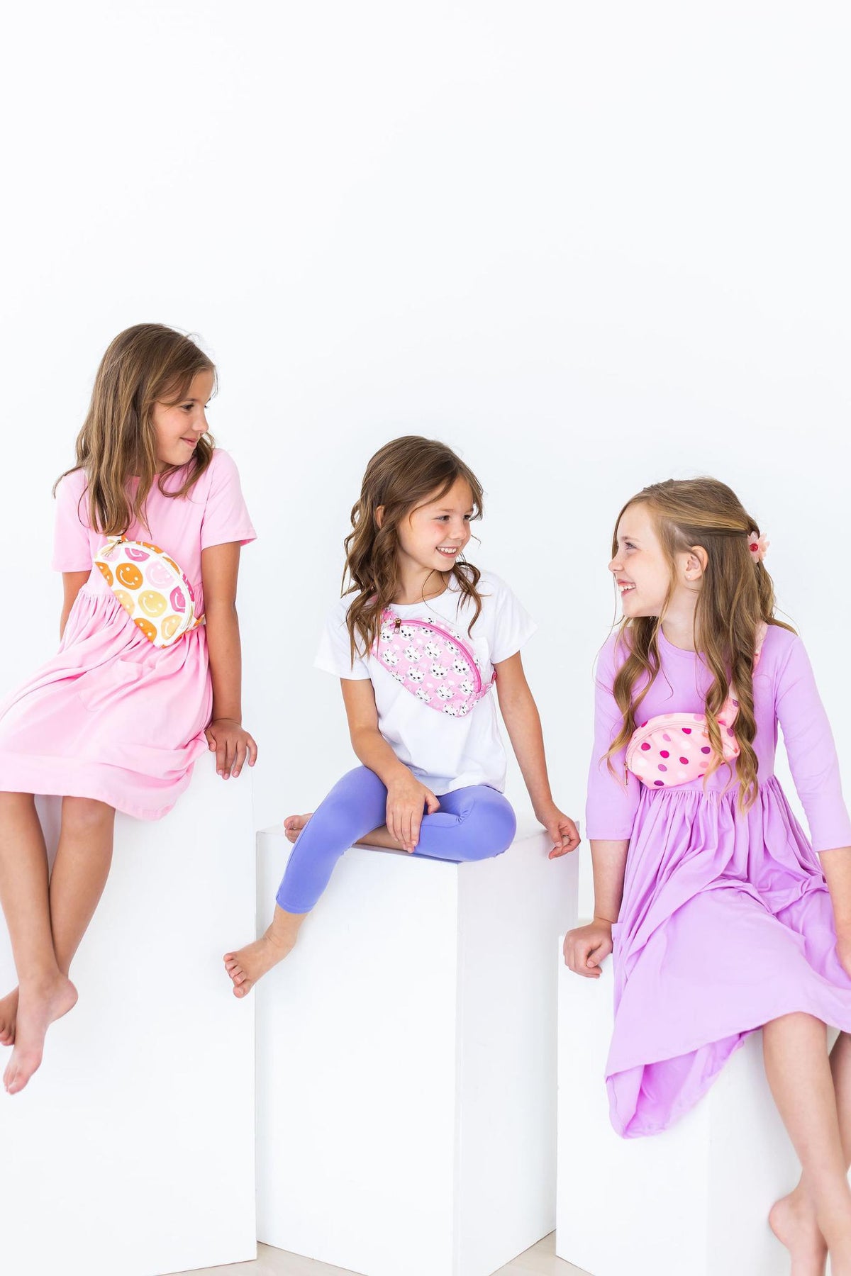 a group of girls sitting on a white cube