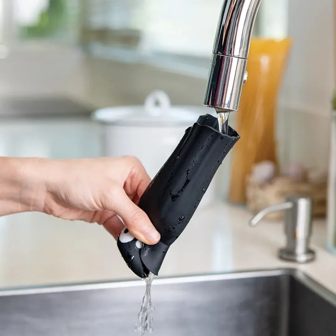 a hand holding a black bag under a faucet