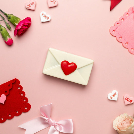 a white envelope with a heart on it surrounded by flowers