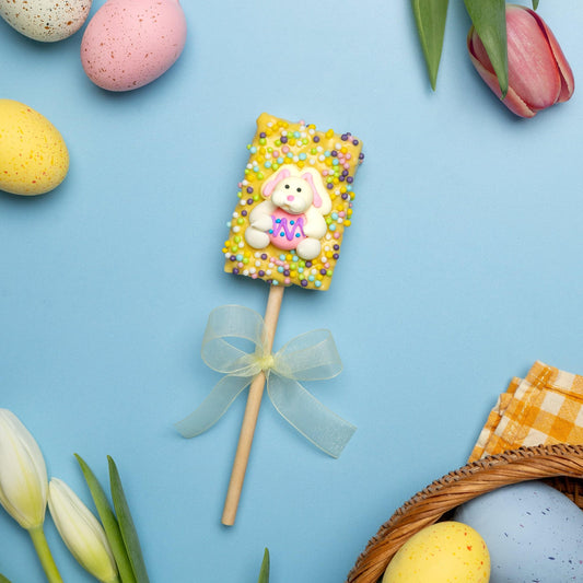 a candy on a stick next to eggs and tulips