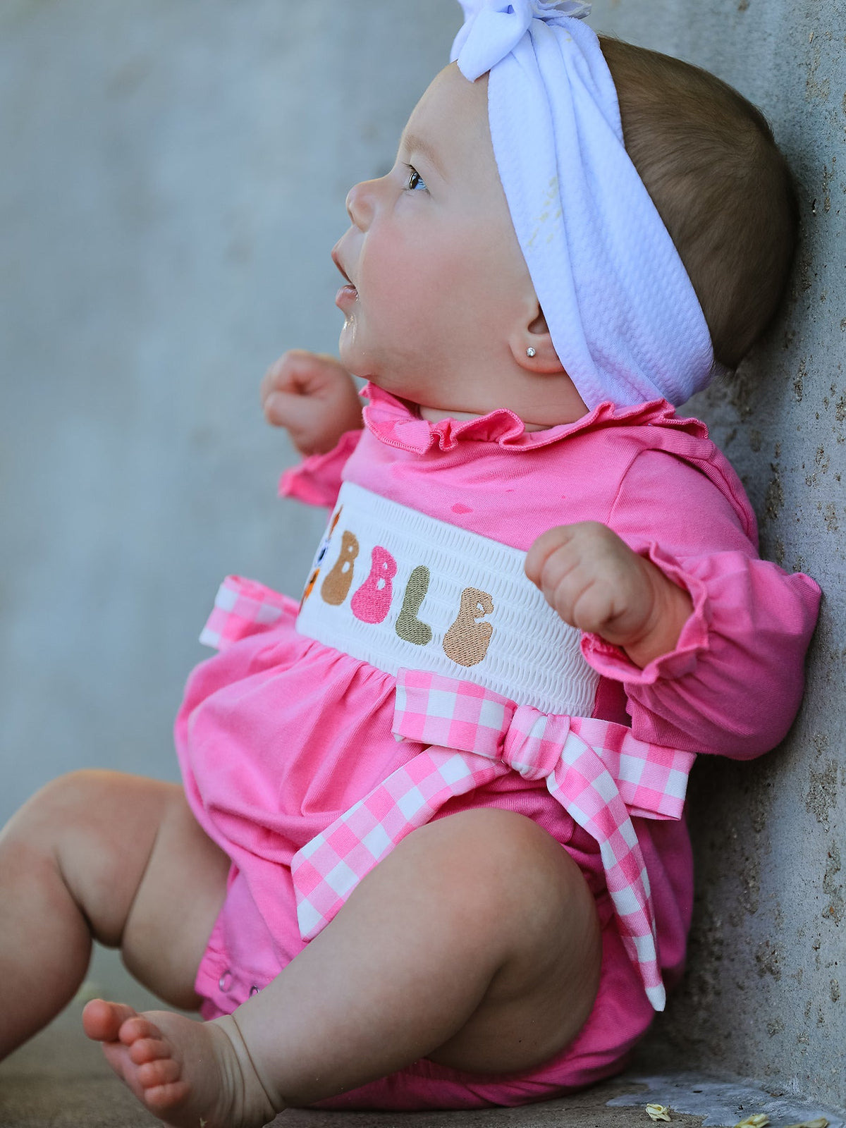 a baby girl in a pink outfit