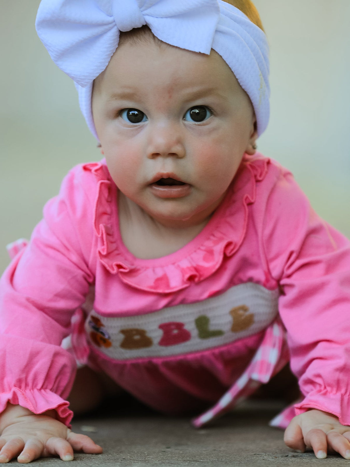 a baby wearing a pink outfit and white hat