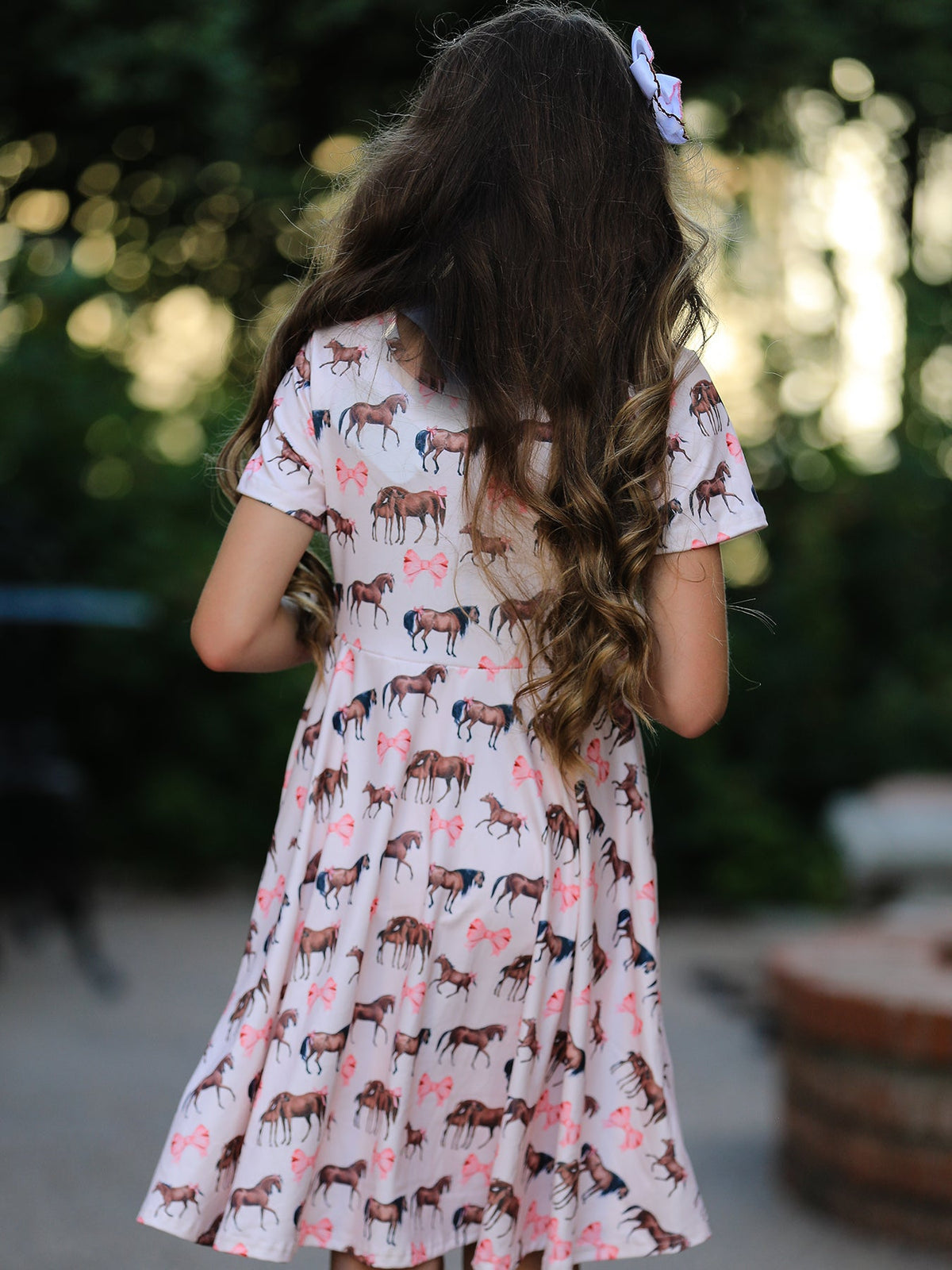 a girl wearing a dress with horses on it