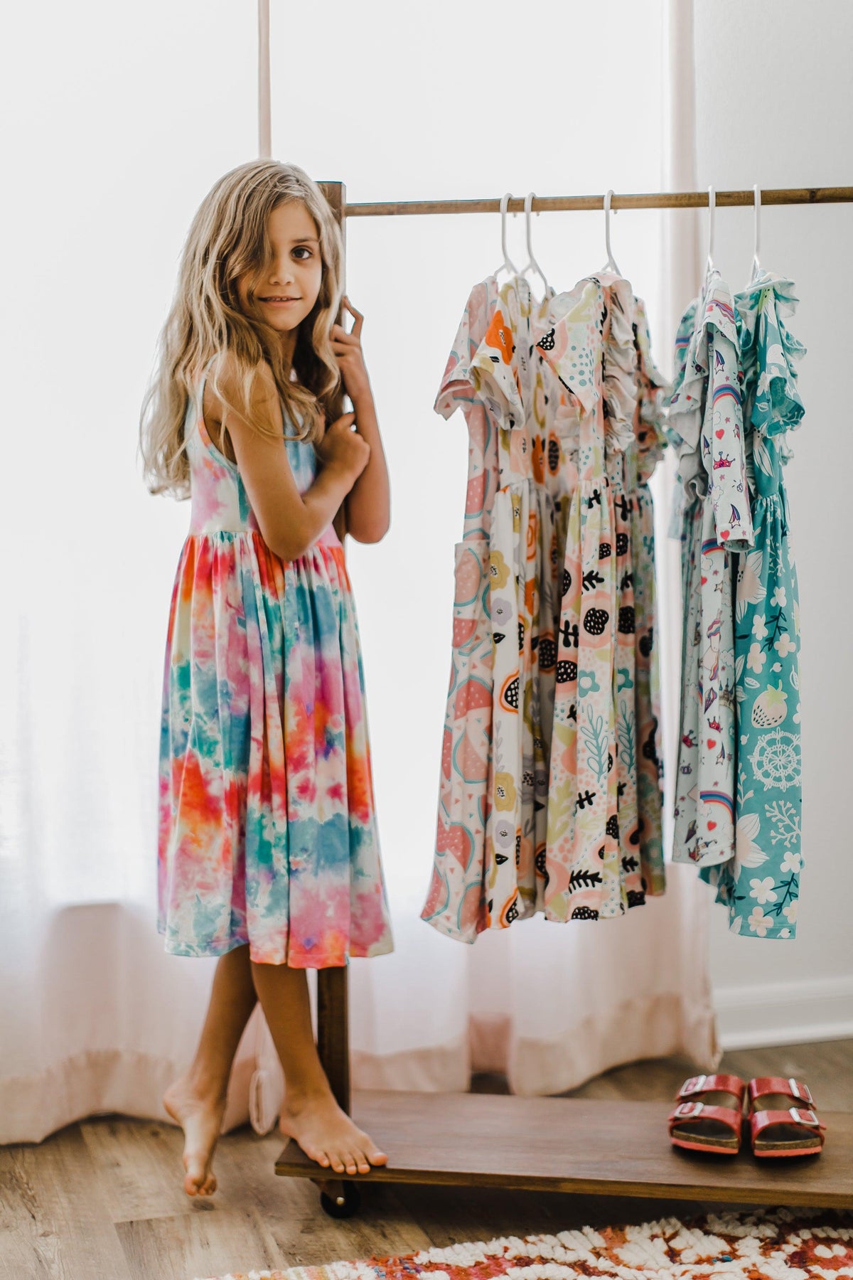 a girl standing in front of a rack of dresses