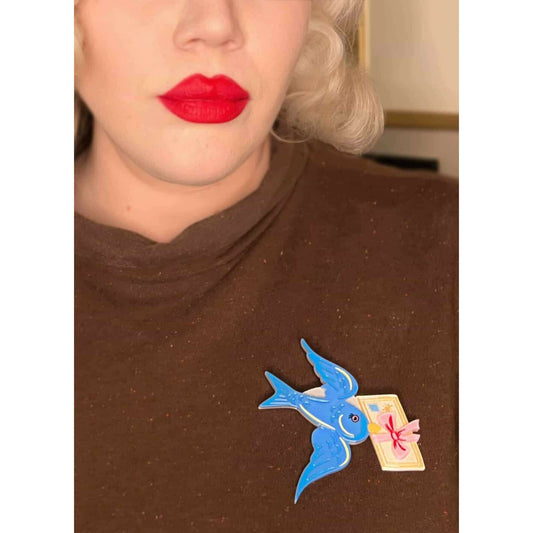 a woman wearing a brown shirt with a blue bird brooch