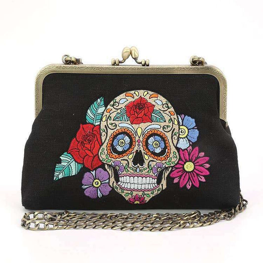 a black purse with a skull and flowers on it